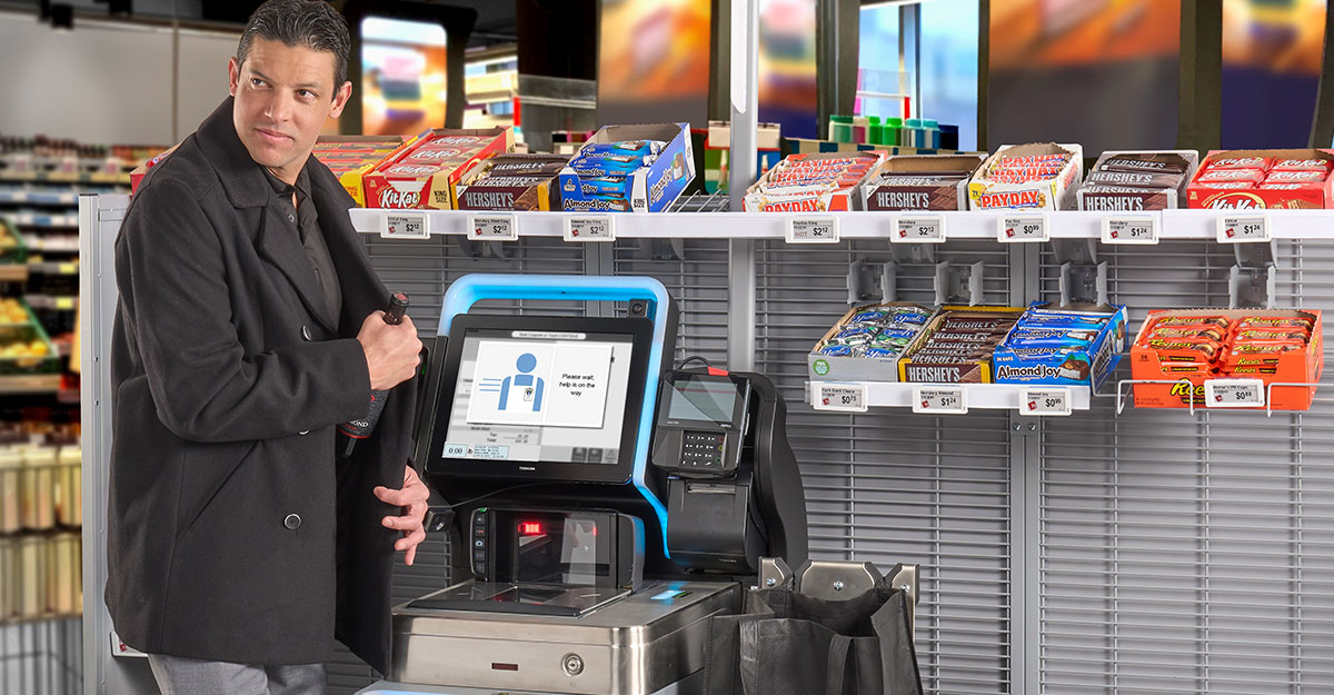 Man putting wine in his coat at a Toshiba System 7 self checkout machine
