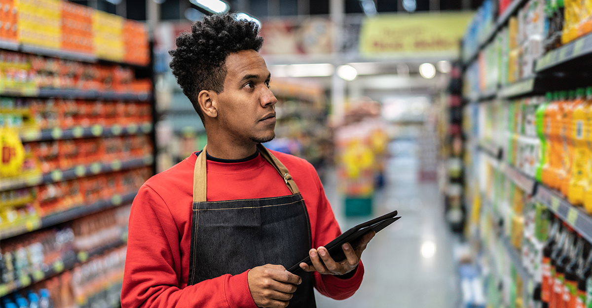 Man confirming inventory on store shelves while holding a tablet